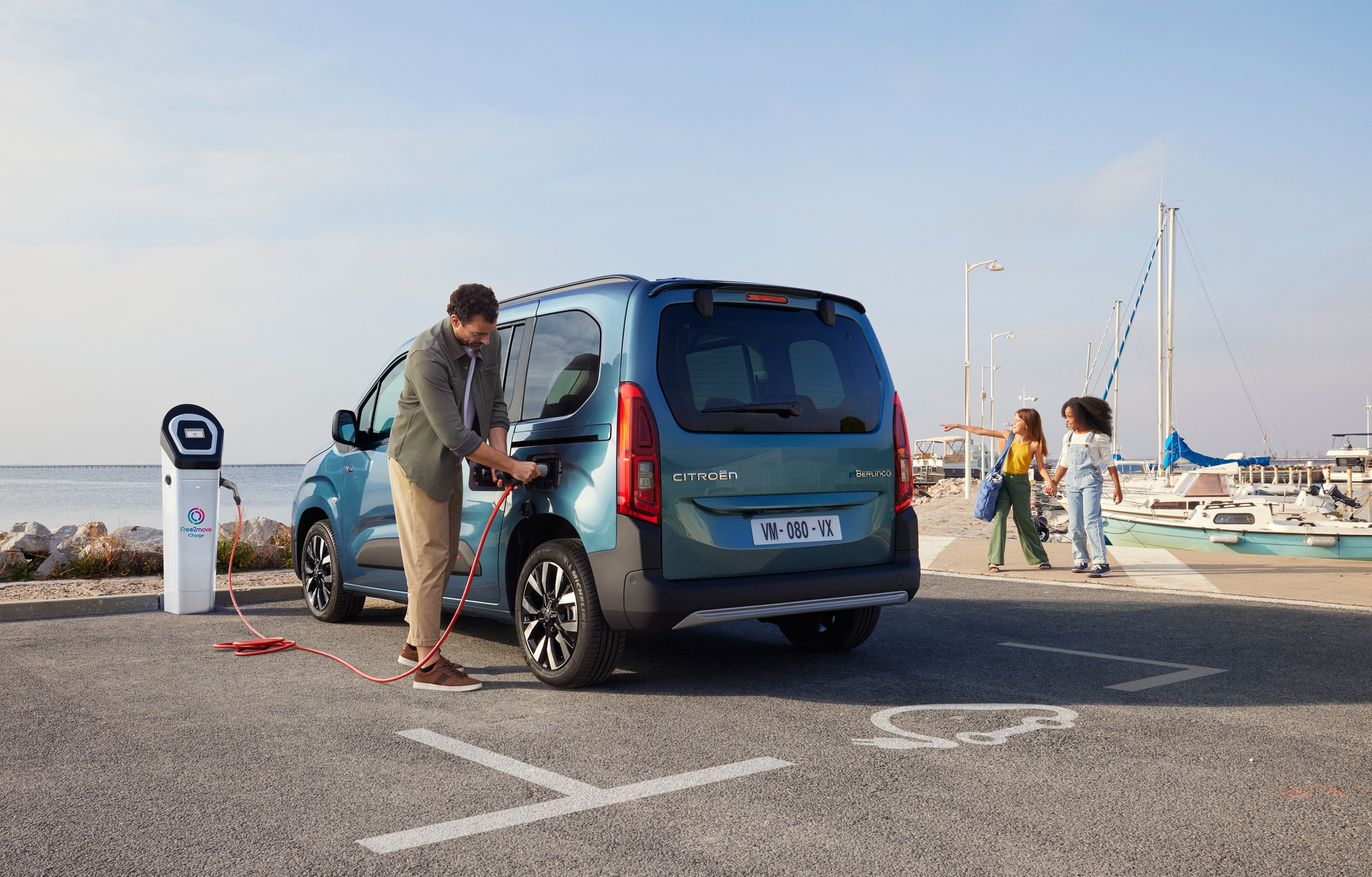 Vista trasera tres cuartos del ë-Berlingo cargando en una estación Free2move mostrando seguridad, eficiencia, tecnología y uso con confianza